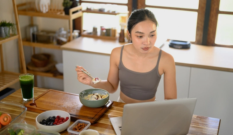 Woman eating a healthy breakfast while working from home