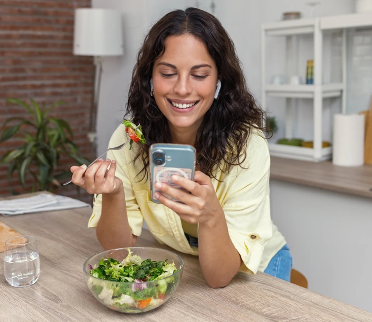 Woman checking her phone while eating a fresh salad