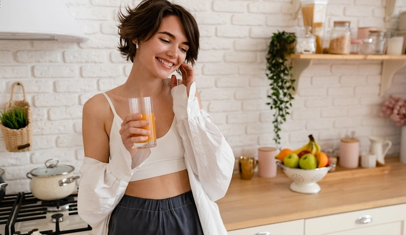 Woman enjoying a fresh fruit smoothie in a bright kitchen