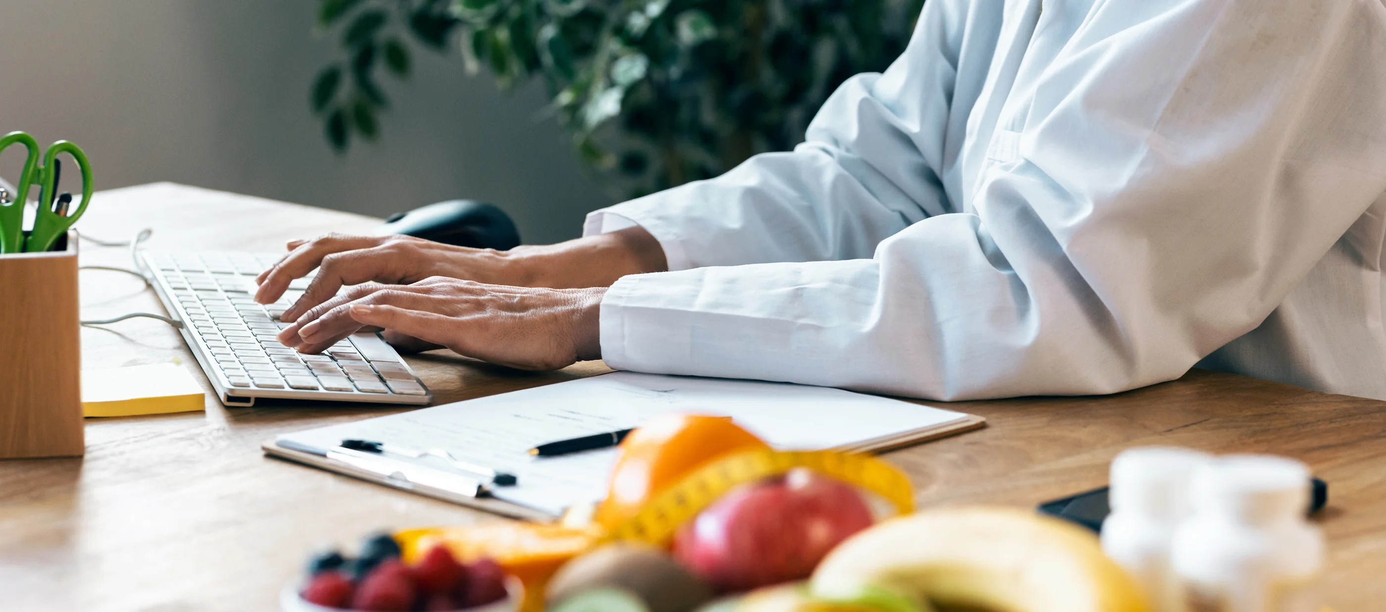 Dietitian working on a laptop beside fresh fruit and nutrition resources