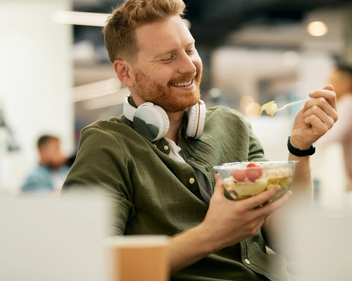 Busy professional wearing headphones while eating a healthy lunch