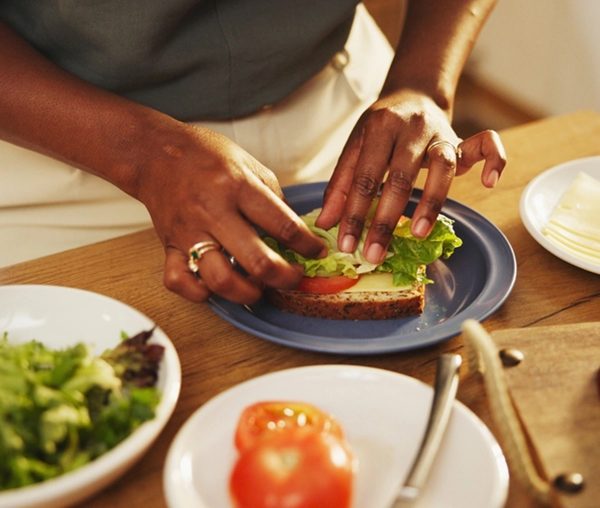 Hands preparing avocado toast with fresh salad ingredients