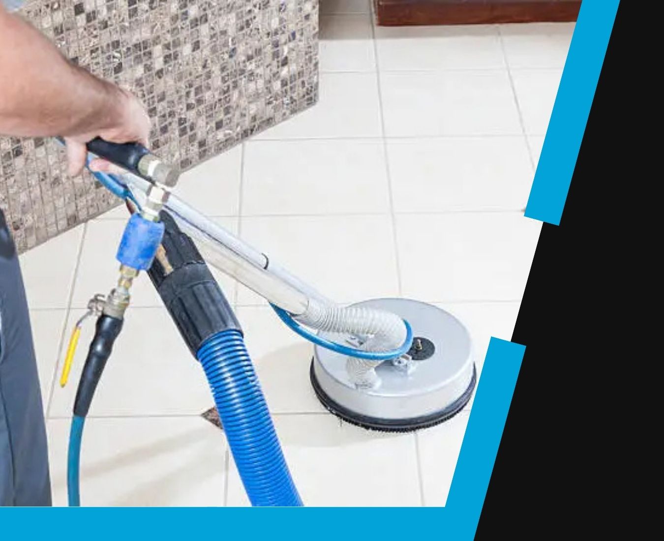 Person using a professional cleaning machine with a blue hose to clean tiled flooring near a wall with mosaic tiles.