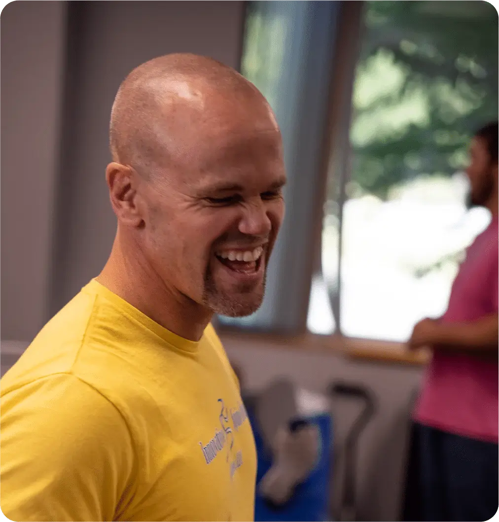 Darby Brighton, owner of Innovative Spine Rehab, smiling in a yellow shirt during a physical therapy session.
