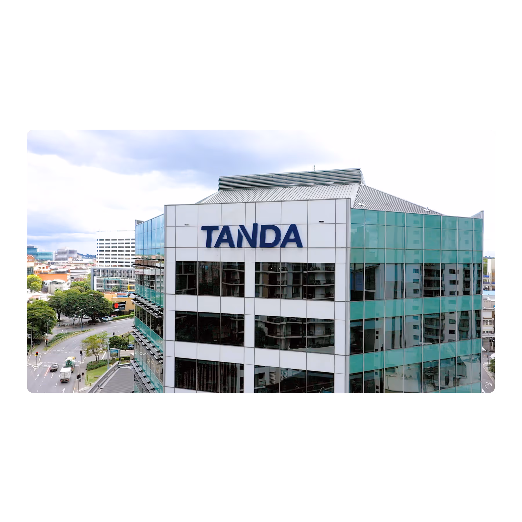 Modern office building with reflective glass windows and TANDA sign on the corner facade.