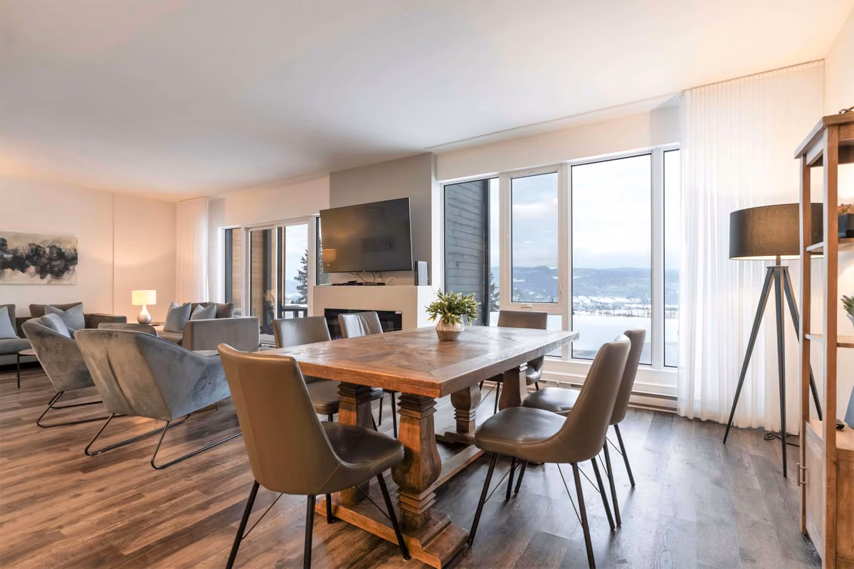 Aire ouverte du condo 108 avec salle à manger et grandes fenêtres, Aurea Charlevoix