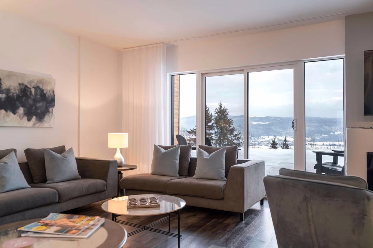 Coin salon du condo 108 face aux fenêtres donnant sur le fleuve, Aurea Charlevoix