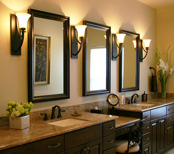 Beautiful dark-wood dual-sink vanity with three custom-framed vanity mirrors flanked by sconce lighting
