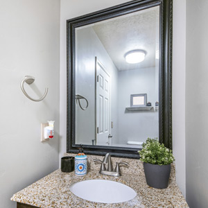 A dark-colored custom-framed mirror above a bathroom vanity.