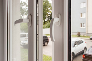 Indoor closeup of handles of an opened white window with double pane glass