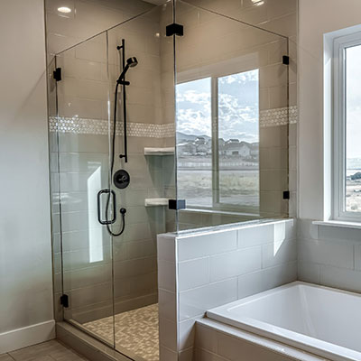 Frameless glass shower with dark bronze fixtures next to a tub in a bathroom.