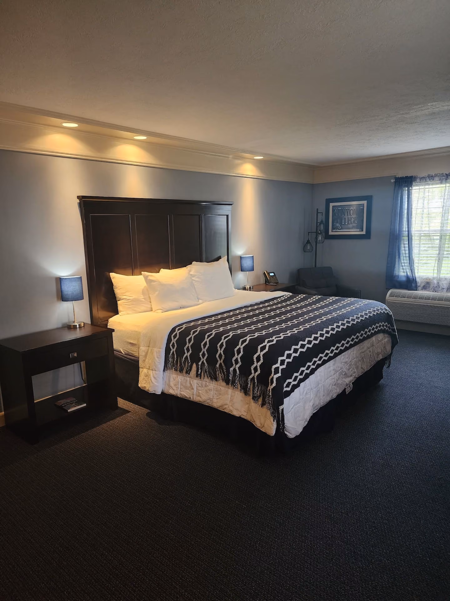 King hotel room at Kenyon Inn & Restaurant featuring modern furnishings, bedside lighting, a sitting area, and a large window.