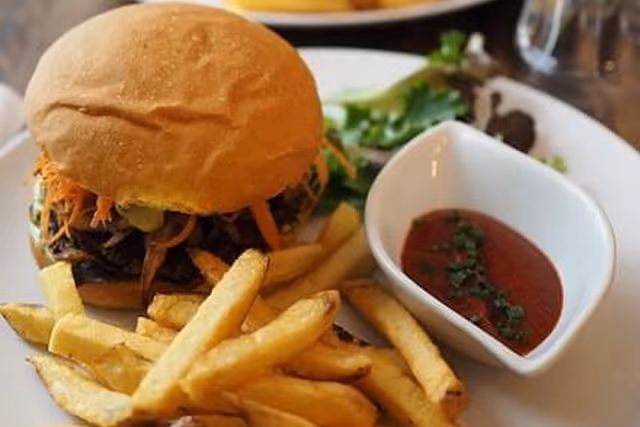 Plate with a burger, French fries, and a small dish of ketchup with herbs on the side.