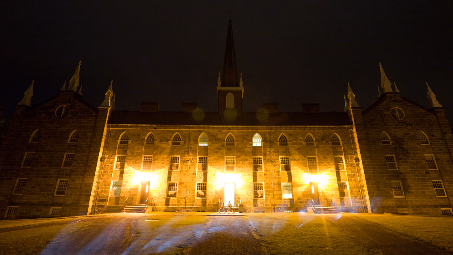 Large historic stone building with bright lights at three entrances during night.