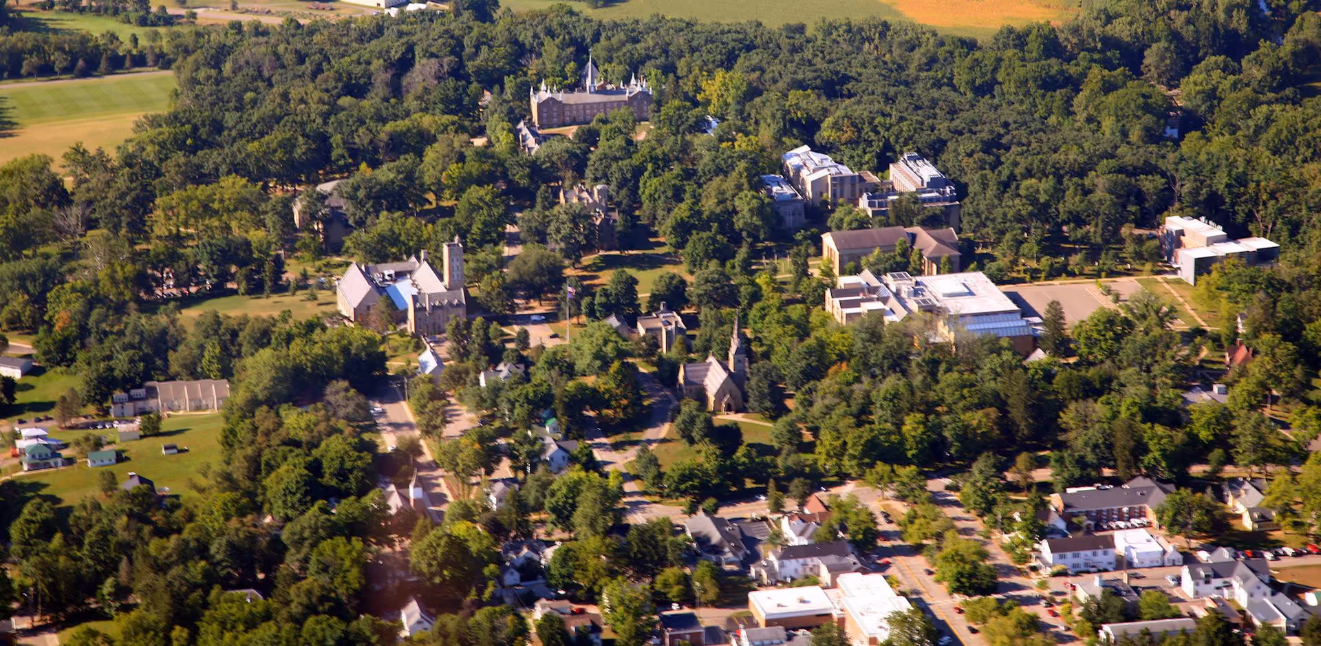 Aerial view of a Gambier, Ohio & Kenyon College with buildings, trees, and surrounding town streets.
