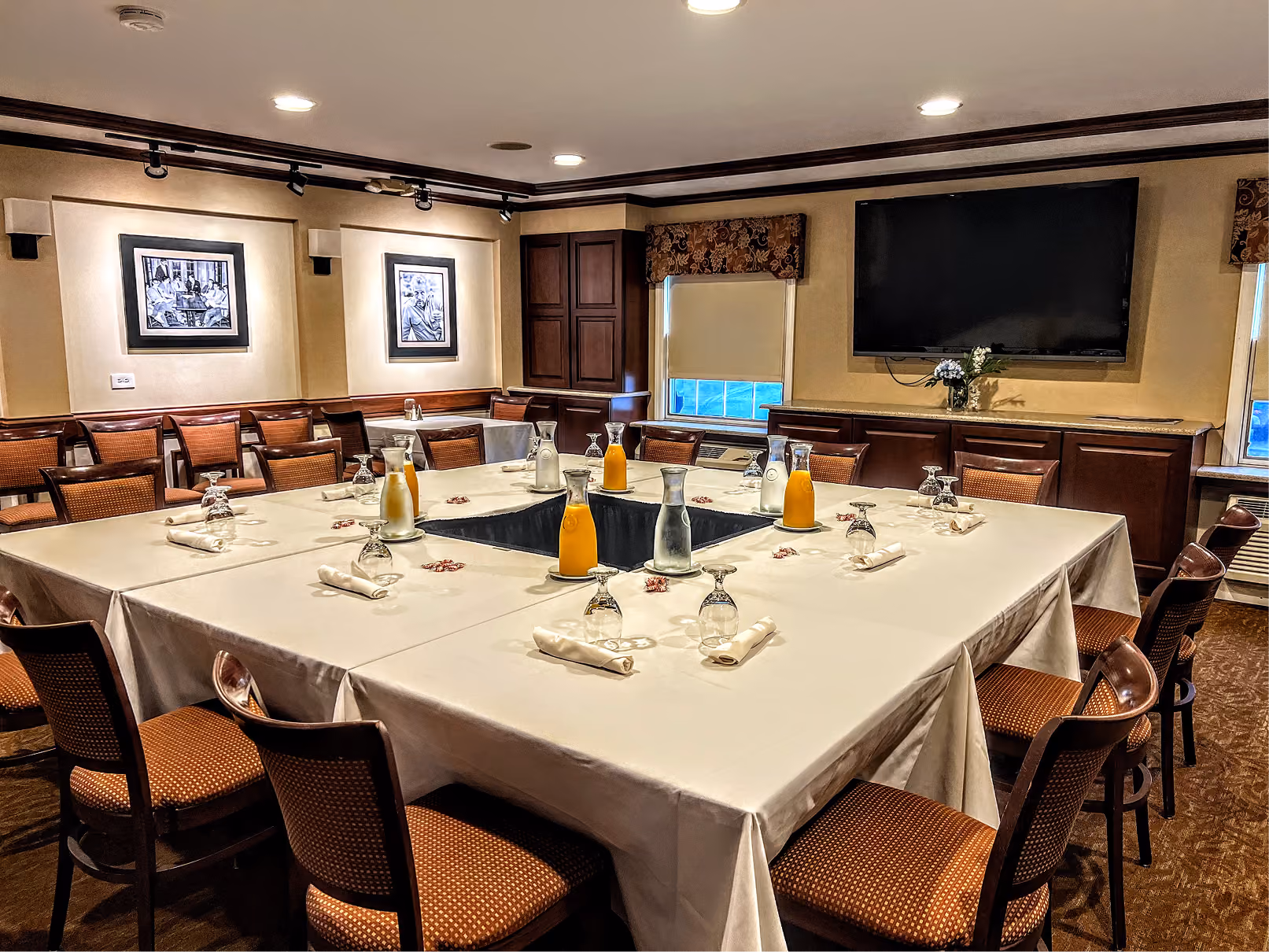 Conference room with U-shaped tables set with glasses, pitchers of water and orange juice, and chairs.