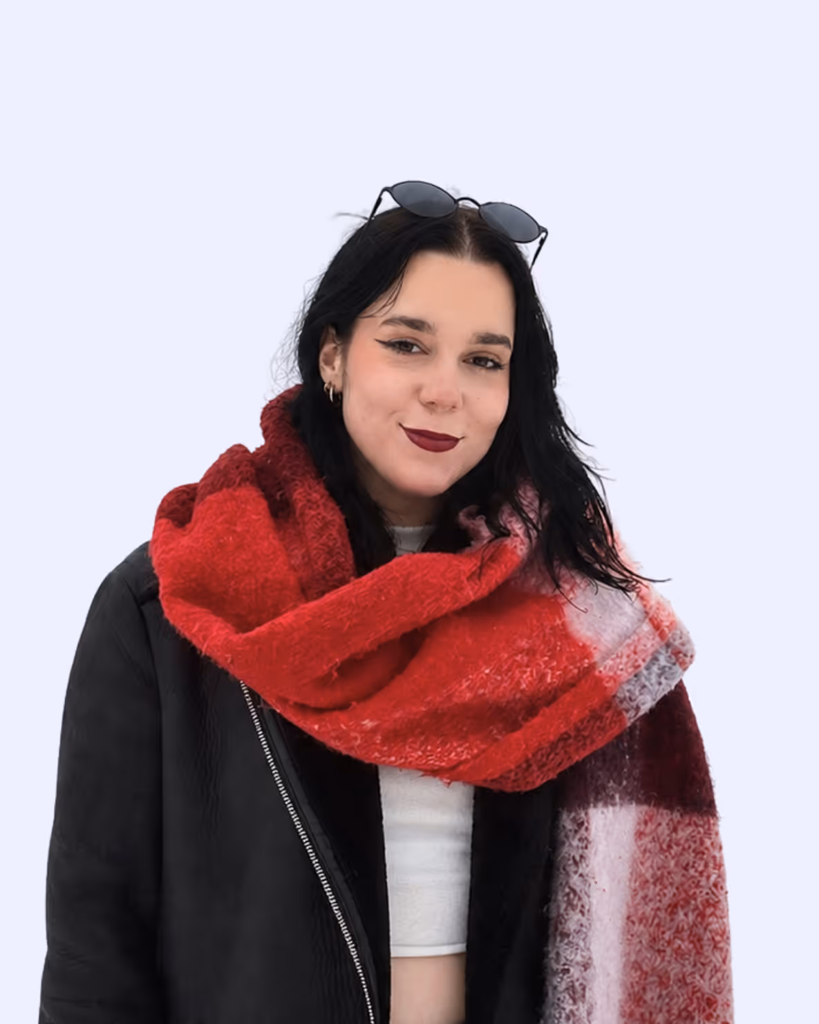 Woman with dark hair wearing red plaid scarf, black jacket, white top, and sunglasses on head.