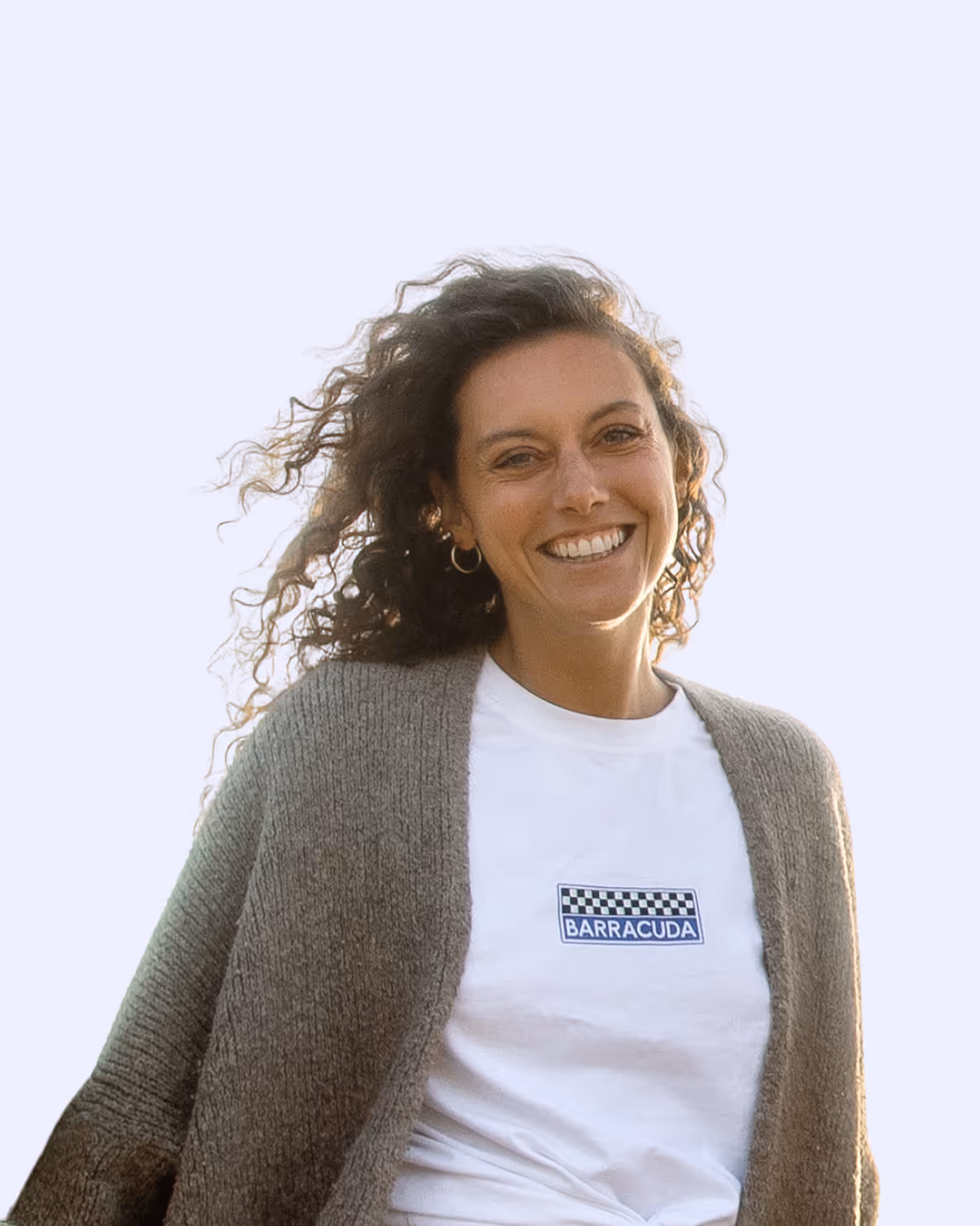 Smiling woman with curly hair wearing a white Barracuda shirt and gray knit cardigan.