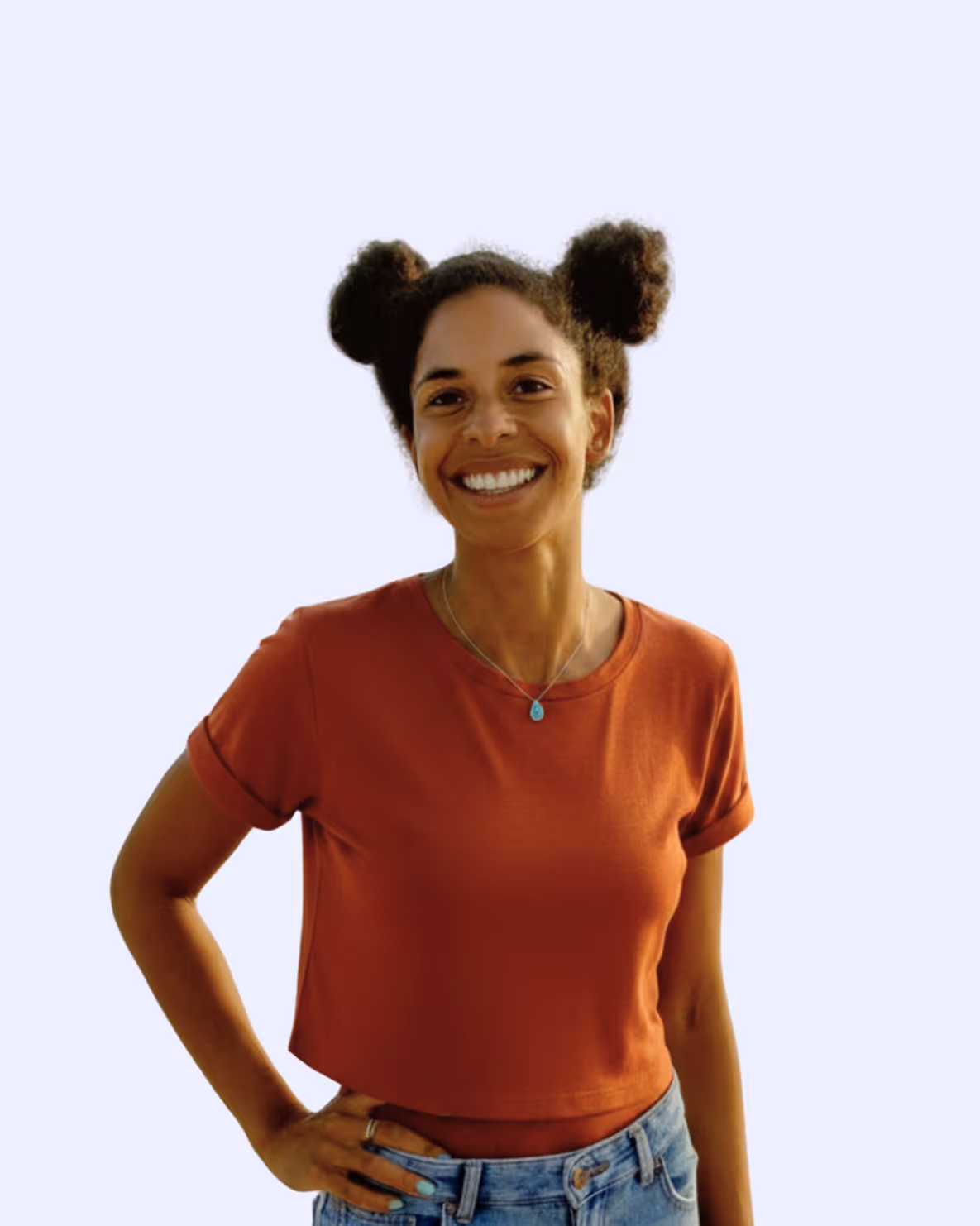 Smiling woman with two hair buns, wearing a rust-colored shirt and denim jeans, hand on hip.