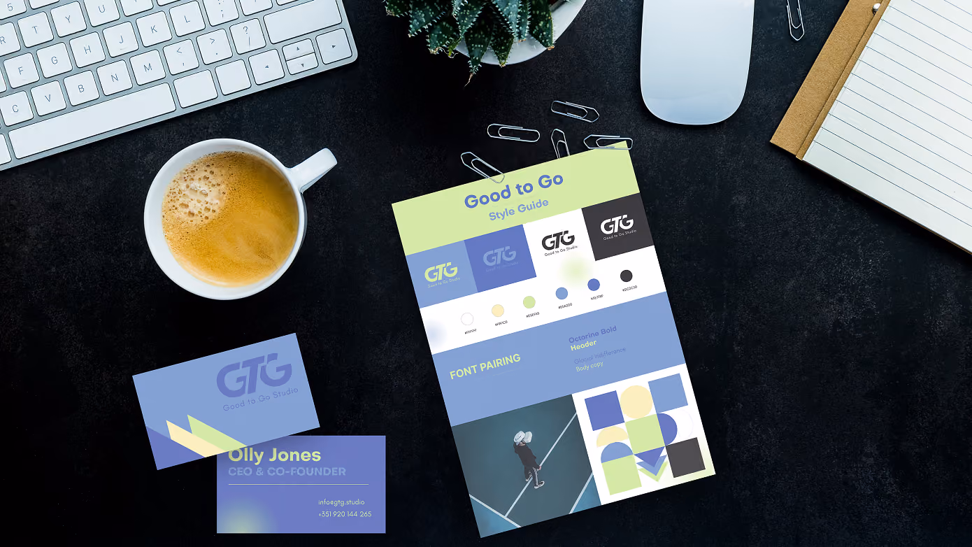 Desk setup with keyboard, mouse, cup of coffee, and Good to Go Studio branding materials including business cards and style guide sheet.