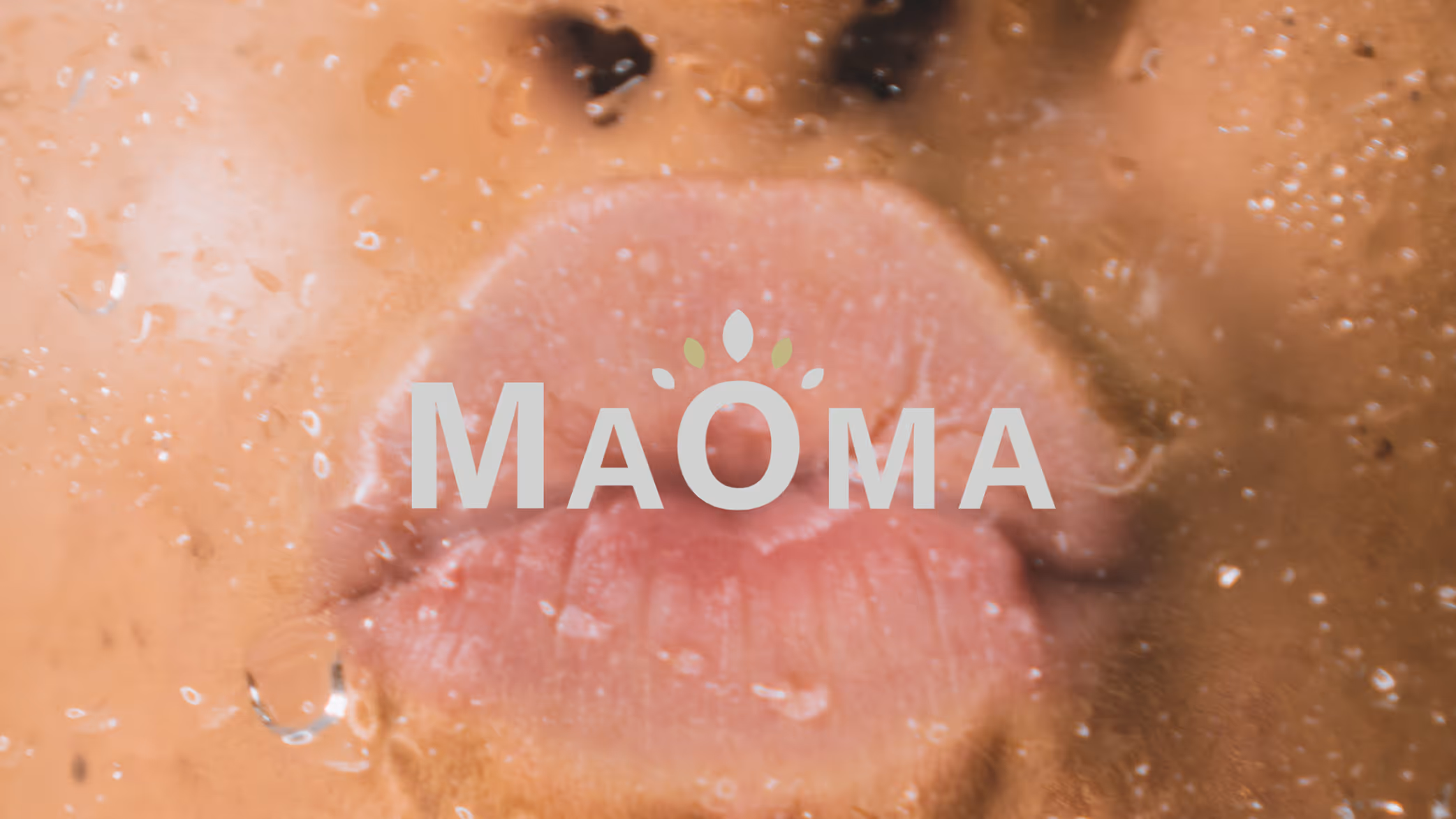 Close-up of a person's lips pressing against a wet glass surface with the text MaOma overlaid.