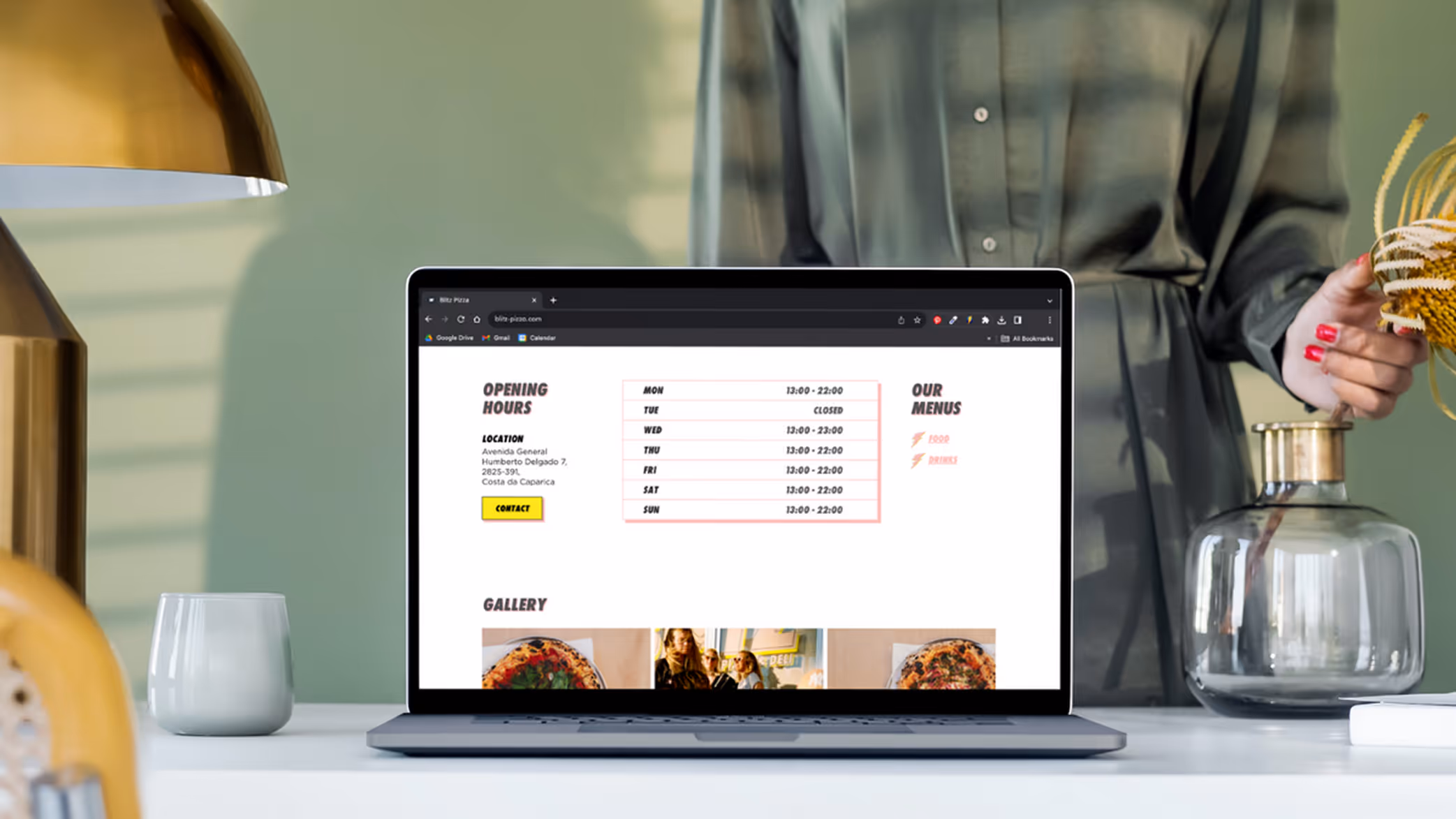 Laptop on a white table displaying Blitz Pizza website with opening hours, location, and menu details.