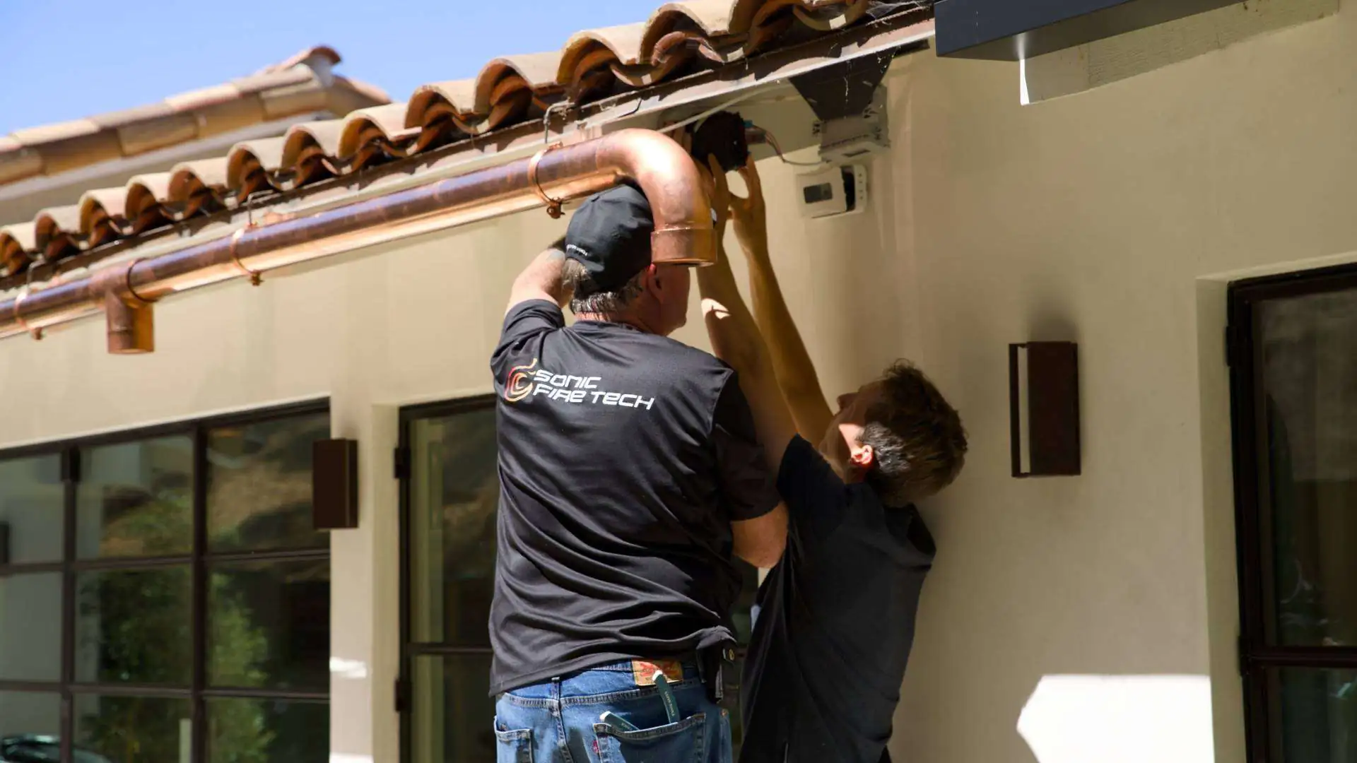 Technicians installing a device under a house's awning