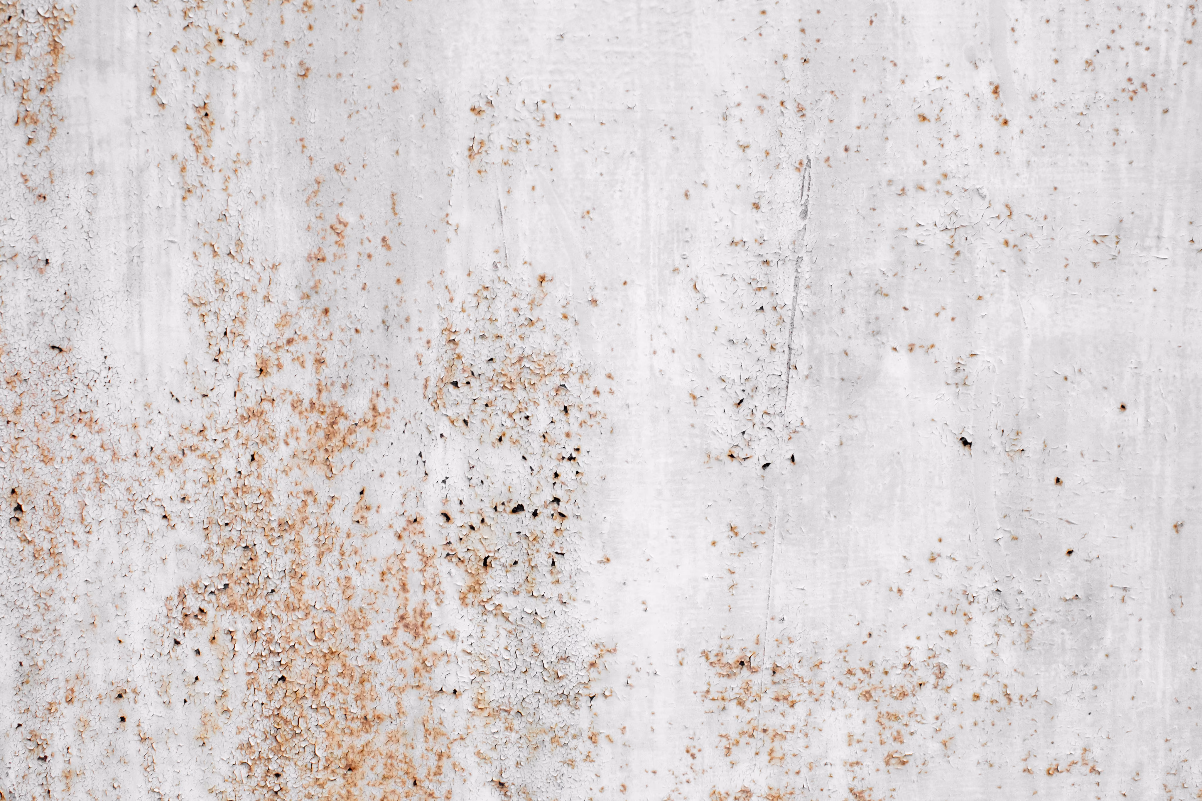 White surface with peeling paint and scattered rust spots creating a textured pattern.