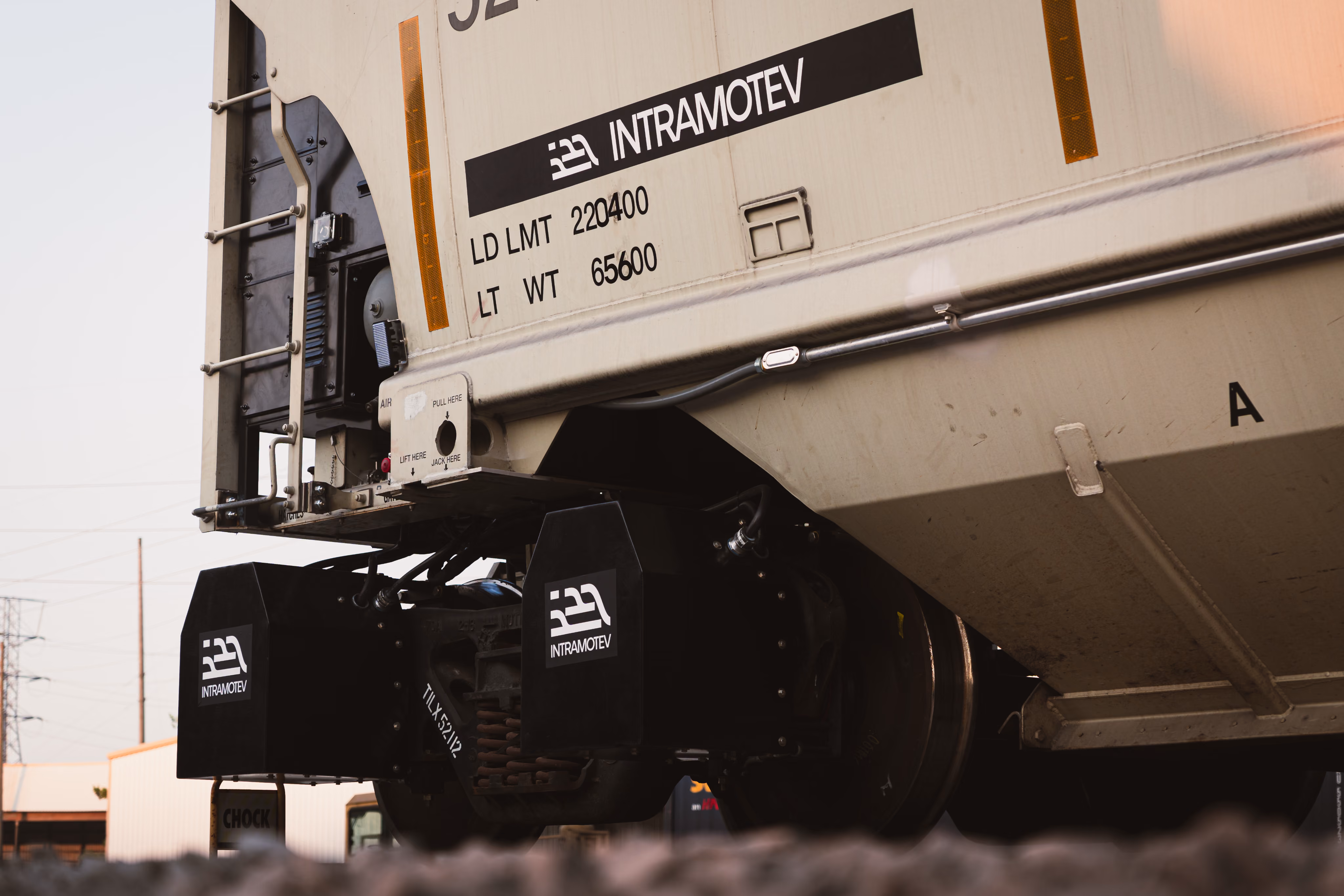 Close-up of a beige railcar with Intramotev electric wheel units and load limits visible.