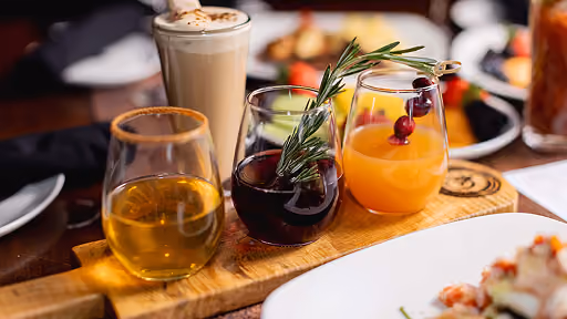 3 flutes of wine with garnish on a wooden serving tray
