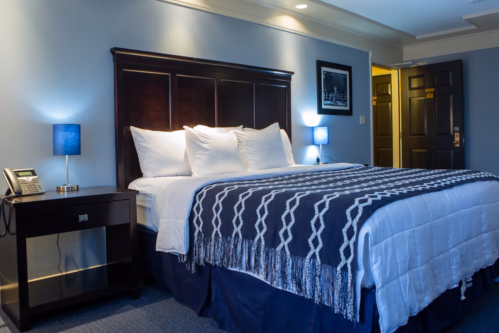 King Jacuzzi room with dark wood headboard, white bedding, navy throw and matching blue bedside lamps