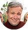 Smiling middle-aged man with gray hair wearing a red shirt outdoors.