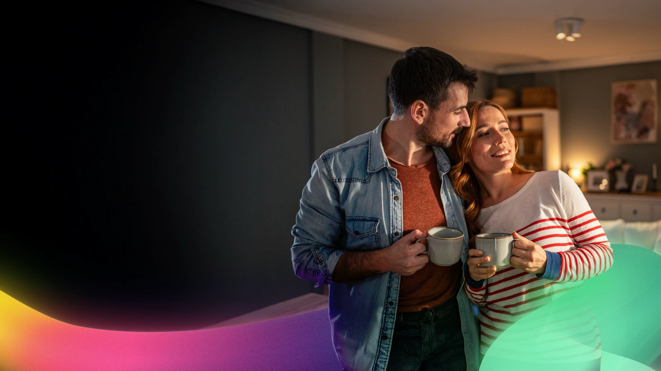 Couple holding coffee mugs, smiling together in cozy home setting