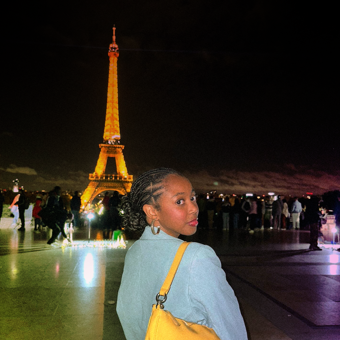 Zariah posing in front of the Eiffel tower at night.