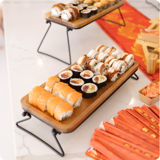 Two wooden trays with assorted sushi rolls placed on a white marble table.