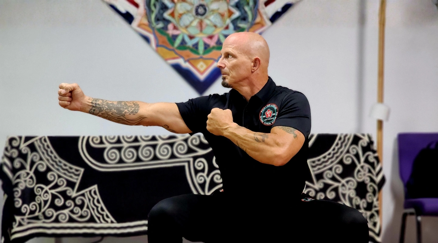 Man in black shirt practicing martial arts strike in studio setting.