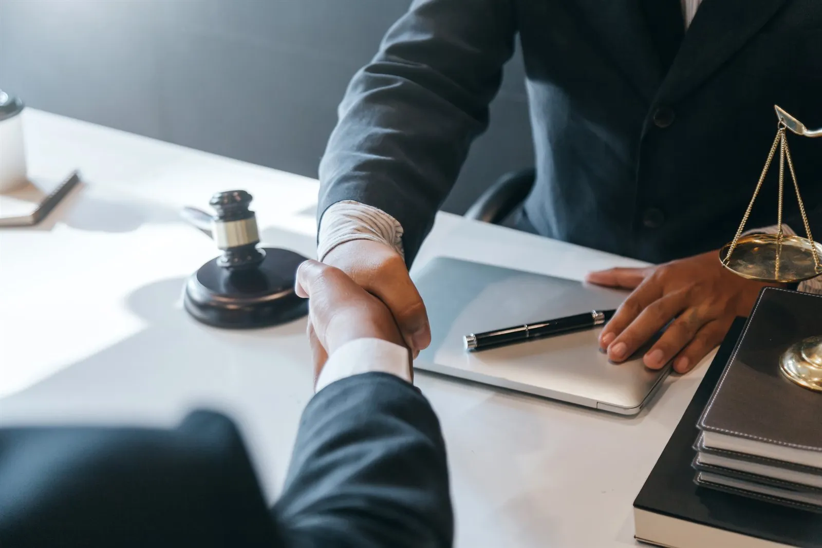 Attorney and client shaking hands beside scales of justice