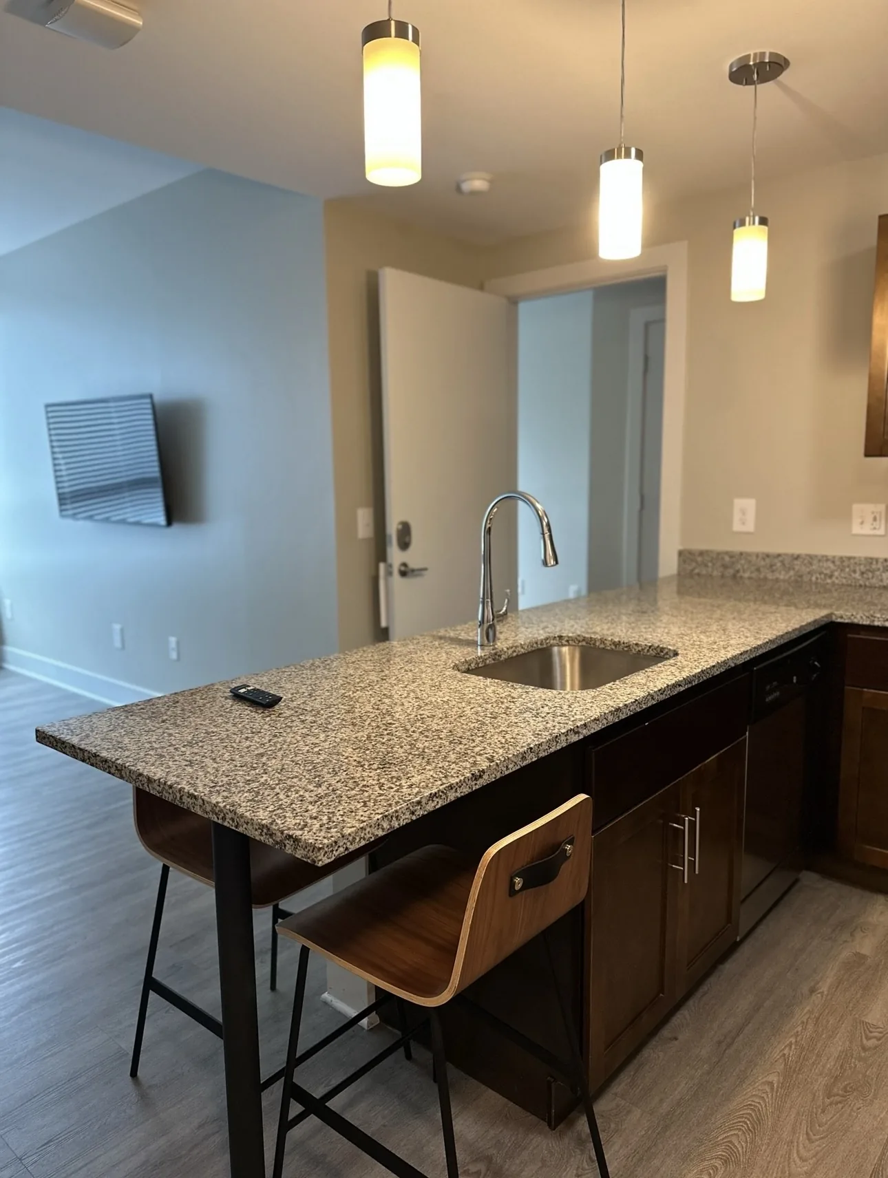 Apartment kitchen with a granite island, sink, and wooden bar stools.