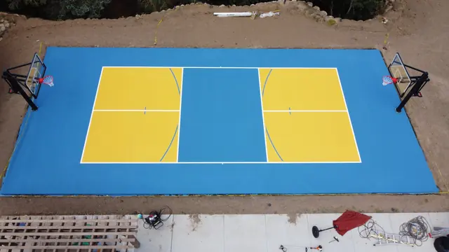 Overhead view of a blue basketball court with yellow playing areas and two hoops.