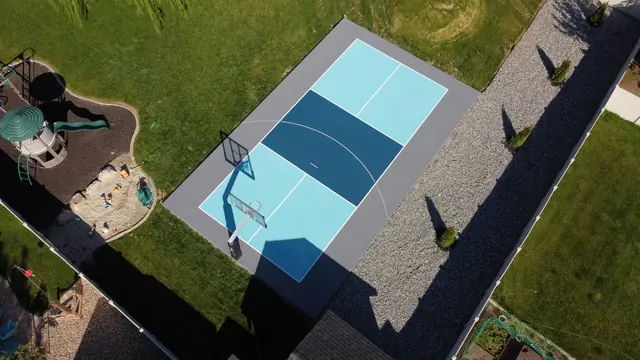 Aerial view of a compact basketball half court with light and dark blue playing areas.