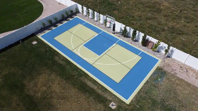 Blue-bordered basketball court with light green playing areas and two hoops.