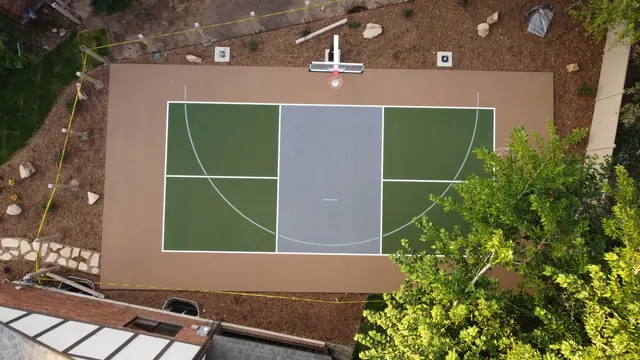 Overhead view of a green and gray basketball half court with tan borders.