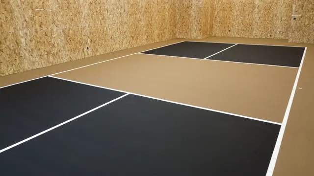 Indoor net court with black playing areas, a tan center and white court lines.