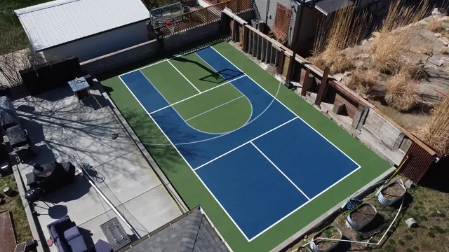 Blue and green backyard court with basketball and net-game markings.