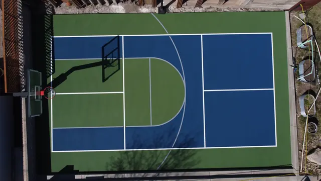 Blue and green backyard court with basketball and net-game markings.