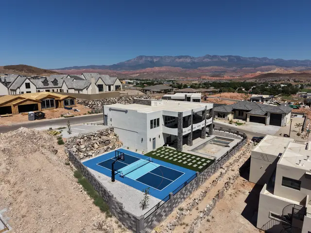Blue backyard court with a light blue center, basketball hoop and net beside stone landscaping.