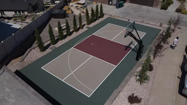 Backyard basketball court with tan playing areas, a burgundy center and dark green border.