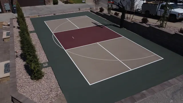 Backyard basketball court with tan playing areas, a burgundy center and dark green border.