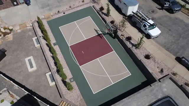 Backyard basketball court with tan playing areas, a burgundy center and dark green border.