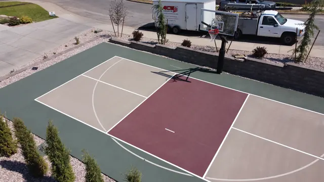 Backyard basketball court with tan playing areas, a burgundy center and dark green border.
